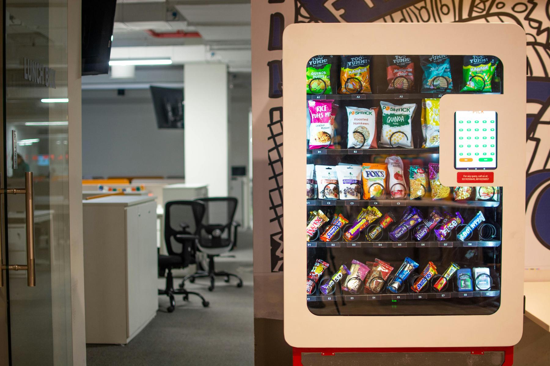 A vending machine in an office with a range of chocolate bars and healthy snacks.