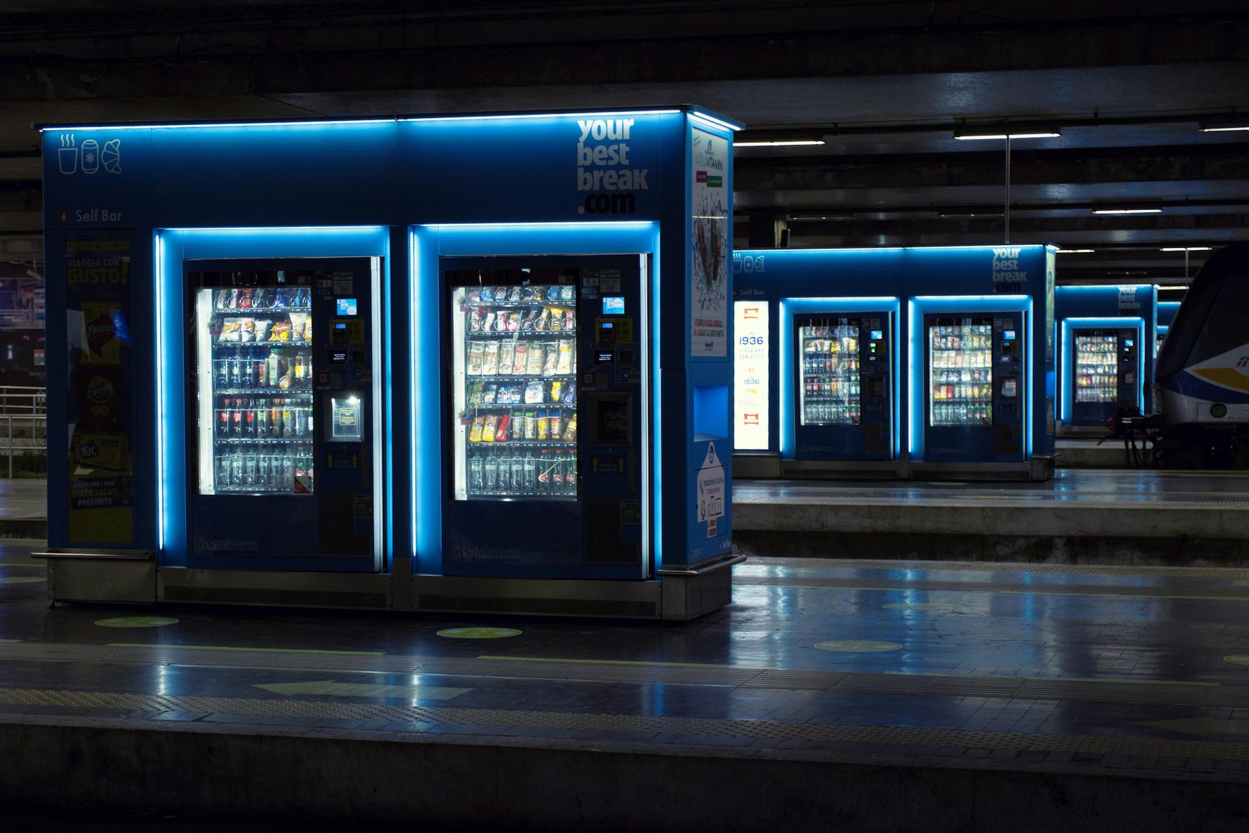 A row of vending machines at a train station which has high foot traffic. 
