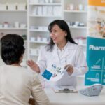 Pharmacist Working In Pharmacy With Customer