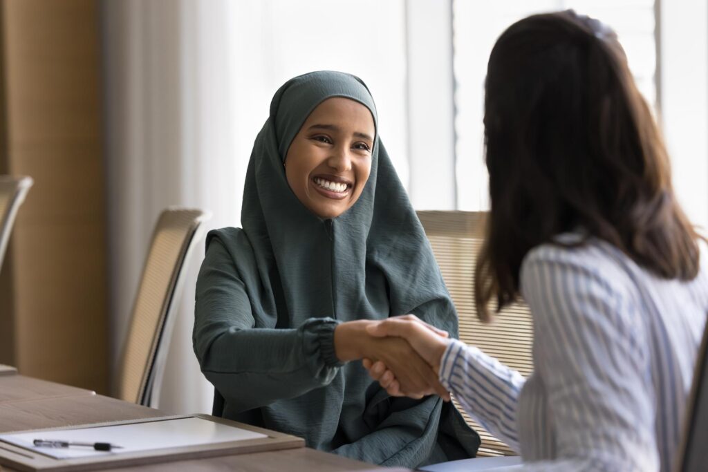 Smiling Arab woman running a social enterprise shaking hands in a board room